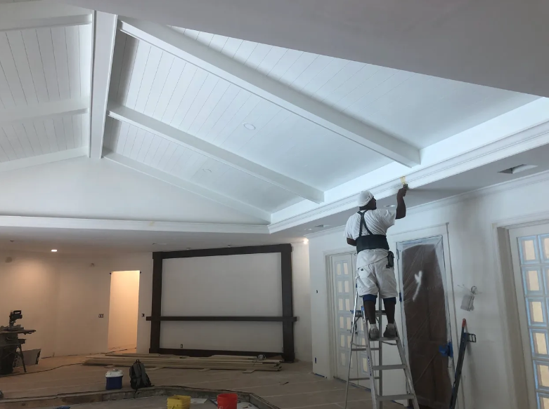 Vital Homes Painting professional applying clean sage-green paint to an interior accent wall with crisp line against white ceiling trim in a Port St. Lucie home.
